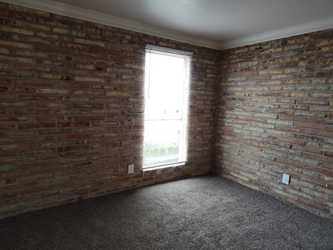 A room with a brick wall and a window.